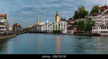 Vista panoramica del Fraumunster e della chiesa di San Pietro con riflessi sul fiume Limmat all'alba, il centro storico di Zurigo, la città più grande della Svizzera Foto Stock