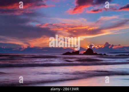 Fiery tramonto in mare. Gale spiaggia onde in movimento. Foto Stock