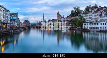 Vista panoramica del Fraumunster e della chiesa di San Pietro con riflessi sul fiume Limmat all'alba, il centro storico di Zurigo, la città più grande della Svizzera Foto Stock