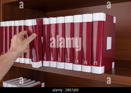 Sul bookshelf man rimuove il libro. Nella libreria. Foto Stock