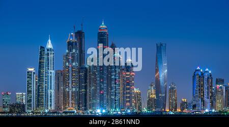 Dubai Marina durante l'ora blu dove le alte e alte torri sono illuminate da luce Foto Stock