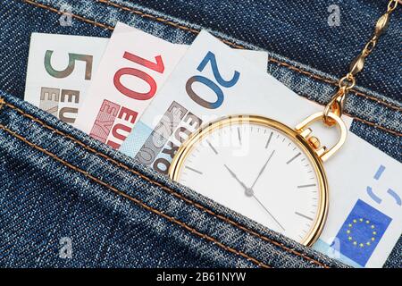 Orologio tascabile con catena in jeans e denaro euro. Primo piano. Foto Stock