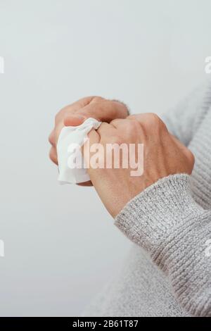 vestirsi di un uomo caucasico, indossando un maglione casual grigio chiaro, disinfettando le mani con una salvietta bagnata Foto Stock