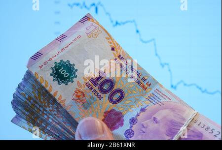 Un fascio di note di peso argentina è simbolicamente tenuto davanti a un computer monitor che mostra il calo del tasso di cambio della valuta argentina. Il tasso di inflazione è attualmente pari al 55%. Il paese ha ridotto la necessità di valuta estera di fermare la fuga di capitali e stabilizzare il peso. | utilizzo in tutto il mondo Foto Stock