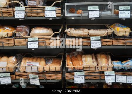 Pane fresco diverso sugli scaffali in panetteria. Interno di un negozio di alimentari moderno che mostra la navata del pane con una varietà di pane preconfezionato ava Foto Stock