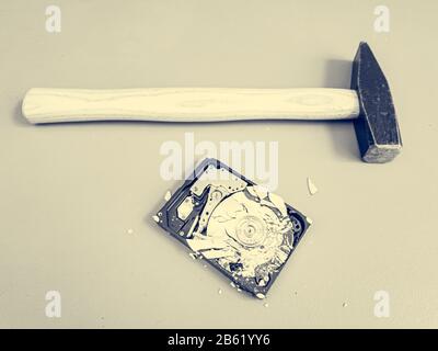 Piatto frantumato nel disco rigido del computer e un martello. Foto Stock