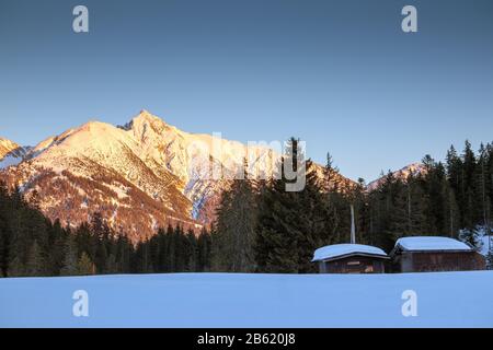 I monti Härmelekopf e Reither Spitze nella stagione invernale. Chalet in legno, neve e foresta di conifere. Paesaggio di Seefeld in Tirolo Alpi austriache Foto Stock