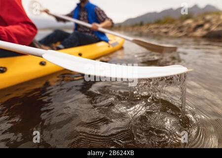 Coppia caucasica facendo kayak e primo piano di pagaie Foto Stock