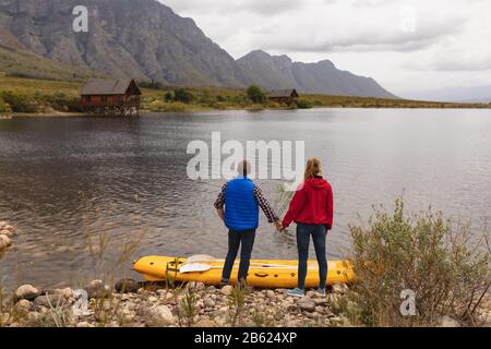 Coppia caucasica godendo della vista del lago vicino al loro kayak Foto Stock