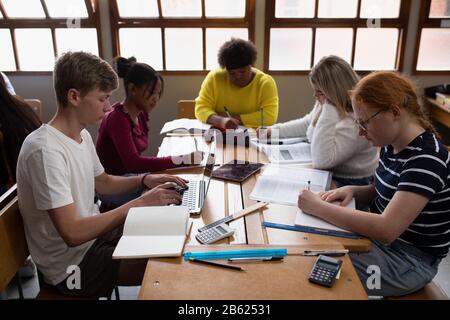 Vista frontale degli studenti che lavorano in gruppo in classe Foto Stock