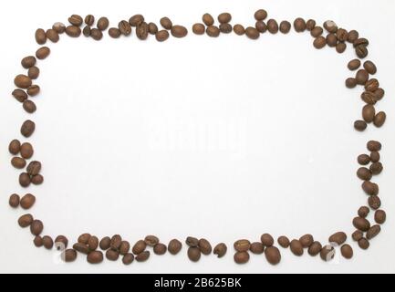 I chicchi di caffè marroni si trovano su uno sfondo bianco sotto forma di cornice rettangolare. Isolato per testo e design. Foto Stock