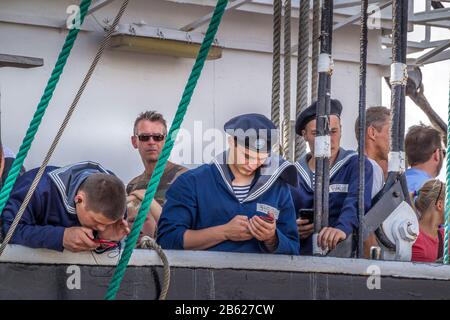 Esbjerg, Danimarca - 02 Agosto 2014: I marinai sono occupati a controllare il telefono cellulare. Le Tall Ships Si Regano nel porto di Esbjerg Foto Stock