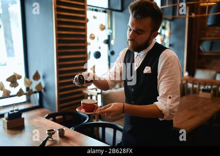 serio uomo duro lavoro in abito elegante concentrato su versare il caffè a terra, primo piano vista laterale foto. talento concetto , persone Foto Stock