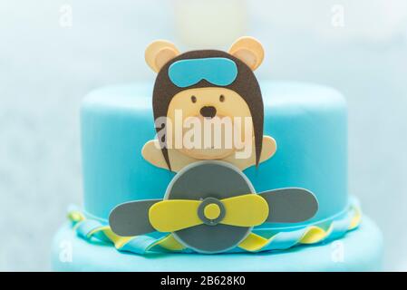 Primo piano di torta blu decorata con carino orso aviatore, aereo e nuvole. Foto Stock