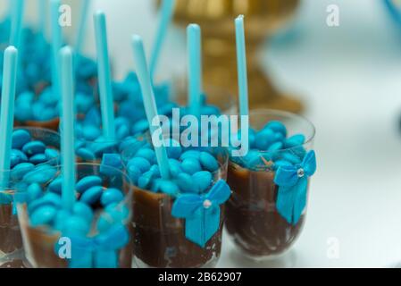 Primo piano di budino al cioccolato marrone in tazza di plastica con cucchiaio blu isolato su sfondo bianco con profondità di campo poco profonda. Dolci al cioccolato serviti Foto Stock