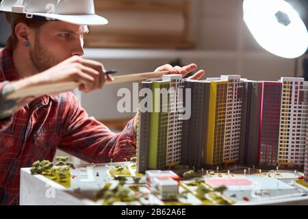 l'uomo ambizioso crea un modello completo di un edificio. primo piano photo.guy in helmst andando a fare cambiamenti nel layout. primo piano foto Foto Stock