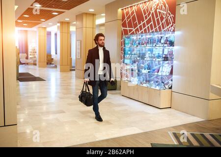 giovane uomo elegante in abiti di moda a piedi in aeroporto, in attesa del volo, tempo di imbarco, foto a tutta lunghezza Foto Stock