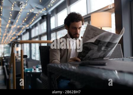 un ragazzo attraente e barbuto che tiene un giornale, che ha un riposo nel caffè. primo piano foto. tempo libero, tempo libero Foto Stock