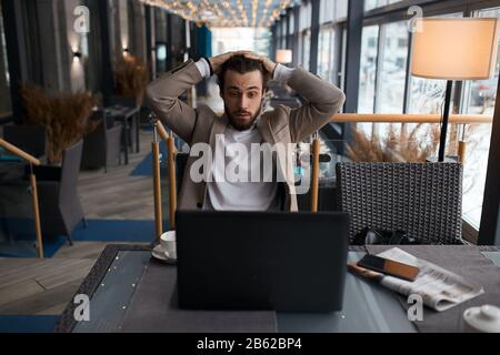 infelice sorpresa uomo che tocca la sua testa guardare video, film al caffè. primo piano foto. tempo libero, tempo libero, lifestyle, passatempo Foto Stock