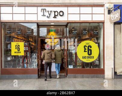 Vendita a Typo negozio nel centro della città High Street negozio, Exeter, Devon, Inghilterra, Regno Unito - due persone entrando porta Foto Stock