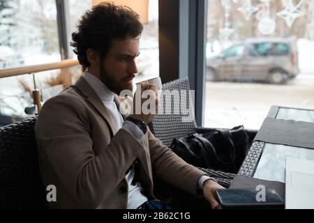 triste ragazzo malcontento sopportato che tiene una tazza di tè, pensando al problema di affari, depressione, fallimento, primo piano vista laterale foto Foto Stock