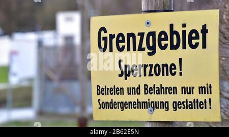 09 marzo 2020, Turingia, Mödlareuth: 'Zona di confine zona limitata! L'ingresso e la guida sono consentiti solo con permesso speciale' è scritto su un segno nel mezzo del villaggio. Il villaggio di 50 abitanti al confine tra Baviera e Turingia era, come Berlino, diviso in due da un muro per decenni. A 100 metri, l'edificio alto più di tre metri è rimasto nel villaggio come parte del museo tedesco-tedesco. Foto: Martin Schutt/dpa-Zentralbild/dpa Foto Stock