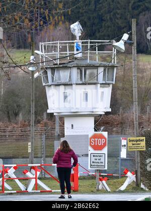 09 marzo 2020, Turingia, Mödlareuth: Recinzioni con filo spinato e una torre di guardia in mezzo al villaggio. Come Berlino, il villaggio di 50 abitanti al confine tra Baviera e Turingia è stato diviso in due da un muro per decenni. A 100 metri, l'edificio alto più di tre metri è rimasto nel villaggio come parte del museo tedesco-tedesco. Foto: Martin Schutt/dpa-Zentralbild/dpa Foto Stock