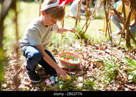 Gruppo Di Bambini Che Indossano Orecchie Bunny Trovare Uova Di Pasqua Nascosti Nel Giardino Foto Stock