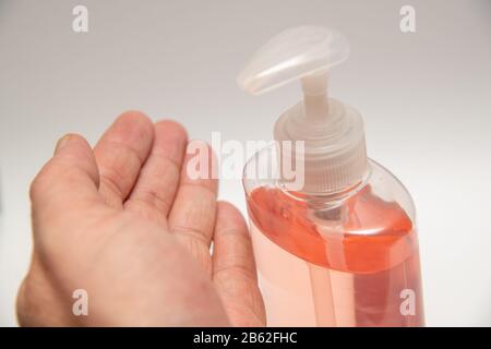 Igienizzatore per mani rosa chiaro in un flacone per pompa trasparente isolato. L'igienizzatore per le mani viene utilizzato per uccidere germi, coronavirus, ecc. Foto Stock