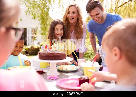 Genitori E Figlia Che Festeggiano Il Compleanno Con Gli Amici Che Hanno Partito In Giardino A Casa Foto Stock