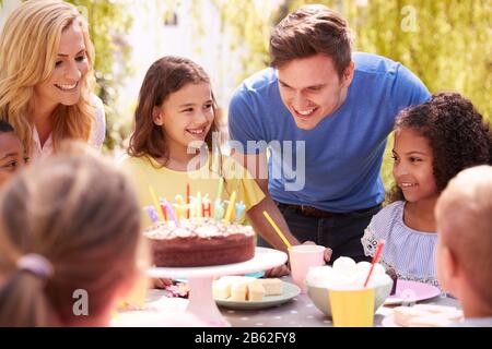 Genitori E Figlia Che Festeggiano Il Compleanno Con Gli Amici Che Hanno Partito In Giardino A Casa Foto Stock
