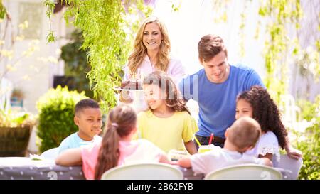 Genitori E Figlia Che Festeggiano Il Compleanno Con Gli Amici Che Hanno Partito In Giardino A Casa Foto Stock