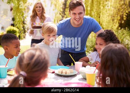 Genitori E Figlio Che Celebrano Il Compleanno Con Gli Amici Che Hanno Partito In Giardino A Casa Foto Stock