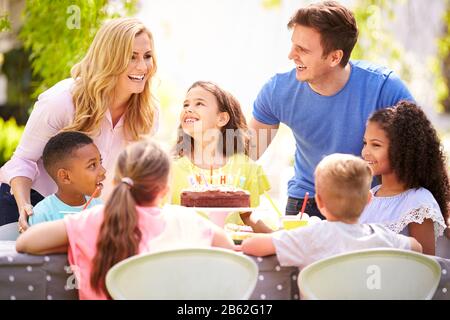 Genitori E Figlia Che Festeggiano Il Compleanno Con Gli Amici Che Hanno Partito In Giardino A Casa Foto Stock