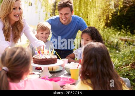 Genitori E Figlio Che Celebrano Il Compleanno Con Gli Amici Che Hanno Partito In Giardino A Casa Foto Stock