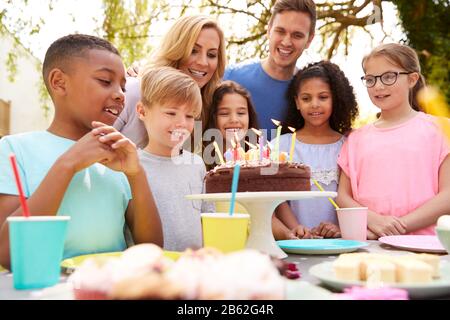 Genitori E Figlio Che Celebrano Il Compleanno Con Gli Amici Che Hanno Partito In Giardino A Casa Foto Stock