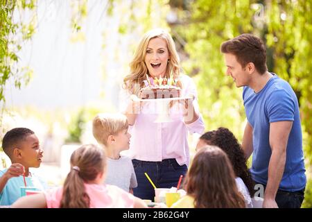 Genitori E Figlio Che Celebrano Il Compleanno Con Gli Amici Che Hanno Partito In Giardino A Casa Foto Stock