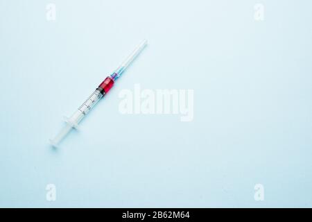 Siringa con una dose. Iniezione parziale su sfondo chiaro Foto Stock