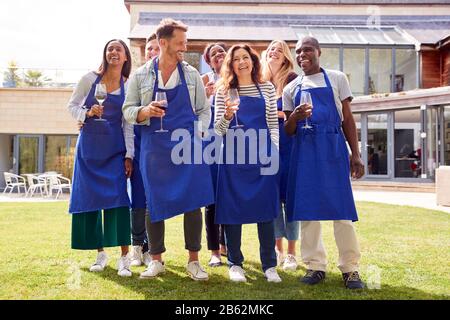 Ritratto Di Gruppo Di Uomini E Donne Che Frequentano La Lezione Di Cucina Rilassante All'Aperto Con Bicchiere Di Vino Foto Stock