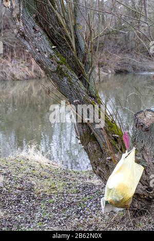 sacchetto di plastica con immondizia appesa su albero in foresta vicino al fiume. inquinamento ecosistema problema , ecologia ambiente rifiuti Foto Stock