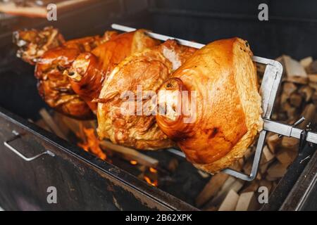 Un grande pezzo di carne di prosciutto Di Maiale è cucinato su un fuoco aperto nella griglia. Street cibo ceco Foto Stock