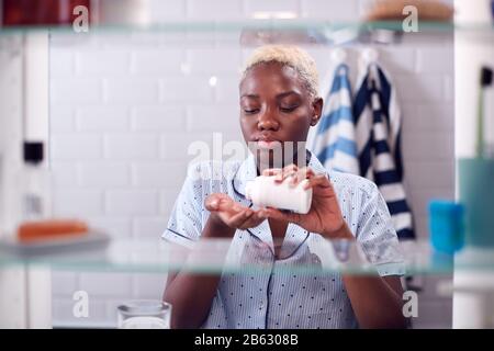 Vista Attraverso Bagno Gabinetto Di Giovane Donna Che Prende Il Farmaco Dal Contenitore Foto Stock