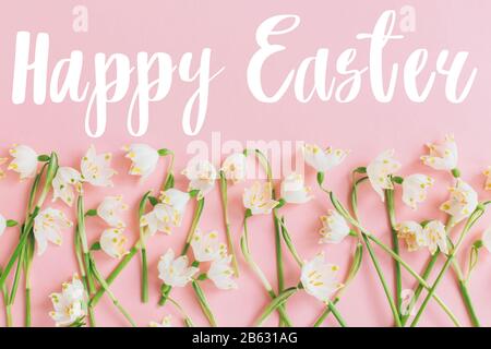 Felice testo di Pasqua su fiori bianchi di primavera su piatto color rosa pastello. Elegante biglietto di auguri creativo per pasqua. Auguri di Pasqua. Banner con scritta Foto Stock