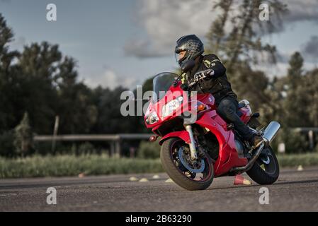 03-09-2019 riga, Lettonia Bellissimo motociclista in pieno equipaggiamento e casco su un rosso e nero. Foto Stock