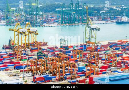 Veduta aerea del porto commerciale di Singapore, delle attrezzature pesanti, dei container, delle gru di trasporto, delle banchine e dei magazzini, del porto con navi e autocisterne Foto Stock