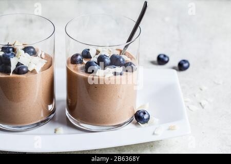 Mousse al cioccolato frullato con frutti di bosco e cocco in un bicchiere per la colazione. Foto Stock