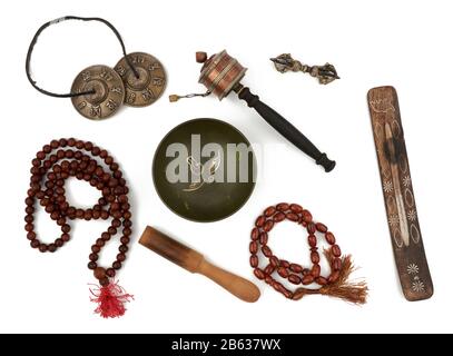 ciotola di canto di rame, rosario, tamburo di preghiera, punitivo, stand di incenso e clapper di legno. Il set per le preghiere e le meditazioni è isolato su un backgroun bianco Foto Stock