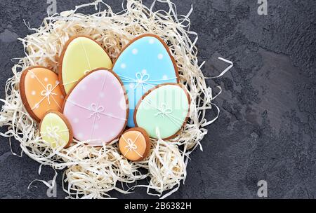 Carta di Pasqua con biscotti di pan di zenzero. Composizione decorativa della primavera di Pasqua con biscotti di pane di zenzero e nido sotto forma di uova su sfondo blu. Foto Stock