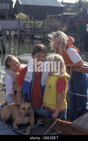 Madre e tre figlie con cani che indossano giubbotti di salvataggio in gommone (fiume Medina, Newport, Isola di Wight) Foto Stock