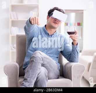 Il giovane uomo di bere il vino in casa Foto Stock